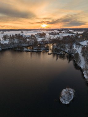 Dikey İHA fotoğrafı gündoğumunda sakin bir kış gölü manzarası yakalıyor.
