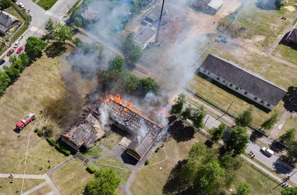 İnsansız hava aracı ile çekilen ahşap bir binanın yangını. Yanan ve dumanı tüten çatı, üst manzara..
