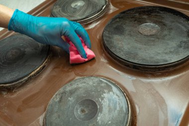 Yoğun kirliliğe sahip elektrik aralığı. Kirli, kahverengi elektrikli sobayı yıkıyor. Elektrikli ocağı temizliyorum..