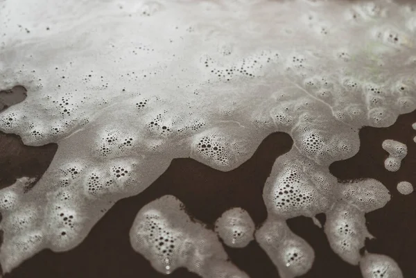 Abstract background with white foam on a colored surface in out-of-focus. Selective focus on cleaning foam. — Stock Photo, Image