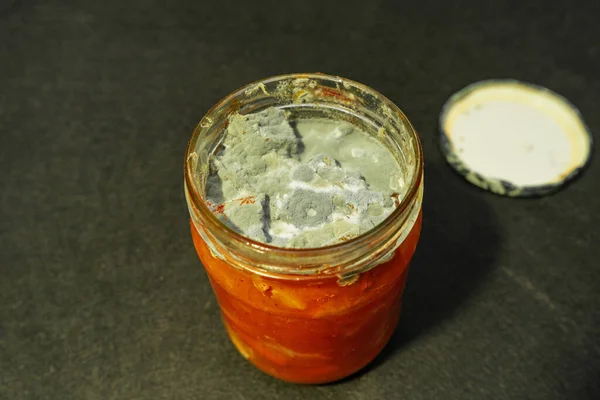 a moldy glass jar of expired orange jam. improper storage of jam