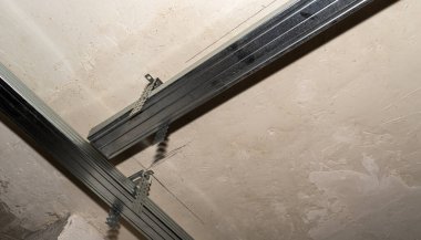 Tavandaki metal çerçeve alçıpan yapıştırmak için. Askıya alınmış alçıpandan yapılmış bir tavan kurulumu.