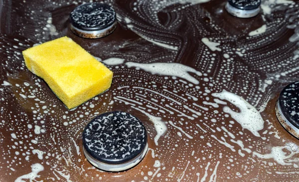 Parlak sarı sünger, gaz sobalarını temizlemek için kimyasal köpük, çözelti, yağ. Yağ ayıklama.