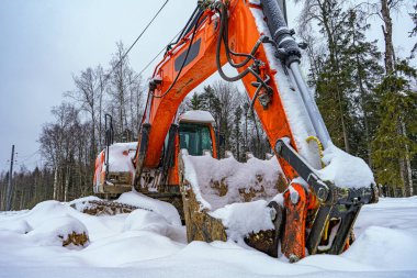 karlı zemine konmuş kovalı turuncu kazıcı.