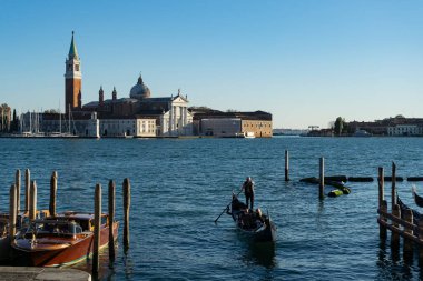 Venedik, İtalya - 10.11.2024: Geleneksel gondol Venedik, İtalya, San Giorgio Maggiore adasının manzarasının tadını çıkaran yolcular.