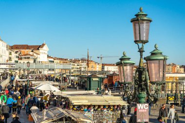 Venedik, İtalya - 10.11.2024: Venedik 'te canlı deniz manzarası, hediyelik eşya tezgahları, sokak lambaları ve turist kalabalığı