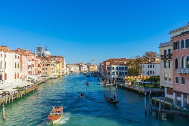 Venedik, İtalya - 10.11.2024: Gondolları, tarihi binaları ve liman kenarındaki kafeleri olan Venedik kanalı