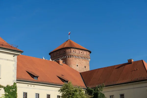 Polonya bayrağı taşıyan Wawel Kraliyet Kalesi Senatör Kulesi, Krakow, Polonya. Mavi gökyüzünün altındaki Wawel Kalesi 'nde tarihi tuğla takviye kulesi.