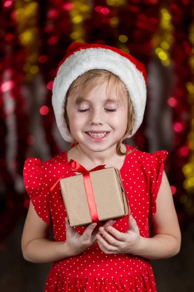 Очаровательная Маленькая Девочка Санта Шляпе Держит Новогодний Подарок Мечтательным Лицом — стоковое фото