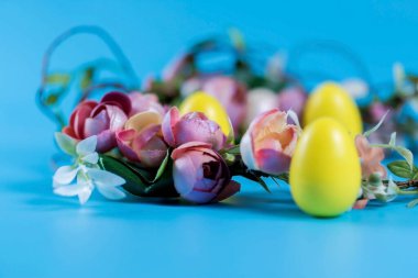 Mavi arka planda renkli Paskalya çelengi ve plastik yumurtalar..