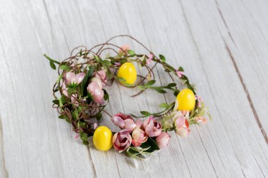 Beyaz ahşap arka planda renkli Paskalya çelengi ve plastik yumurtalar..