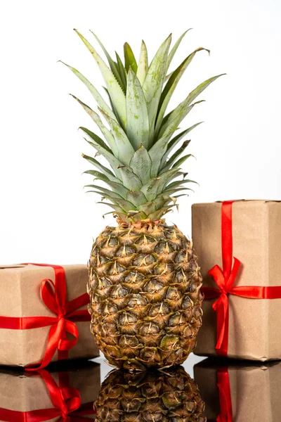 Piña fresca y cajas de regalo sobre mesa de vidrio negro sobre fondo blanco —  Fotos de Stock