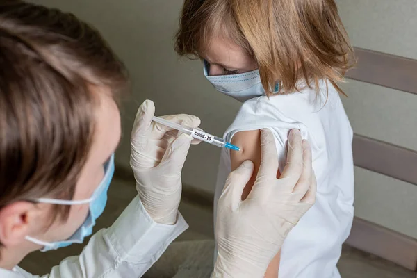 Covid-19 ya da Coronavirus 'a karşı çocuklar için antivirüs aşısı. Küçük kız bir erkek doktor tarafından koronavirüse karşı aşı oluyor..