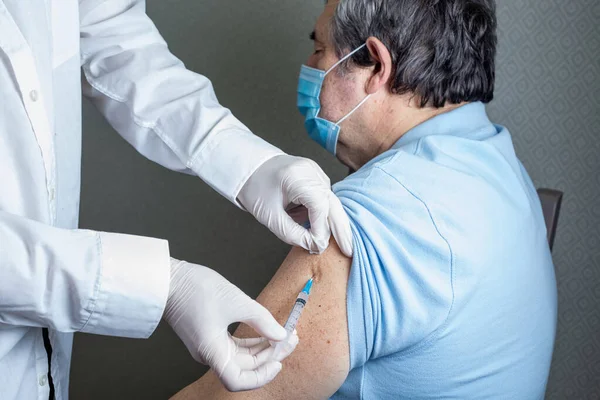 Klinikteki yaşlılar için antivirüs aşısı. Yaşlı bir hastayı grip, grip, zatürree veya koronavirüse karşı aşılayan pratisyen hekimler.