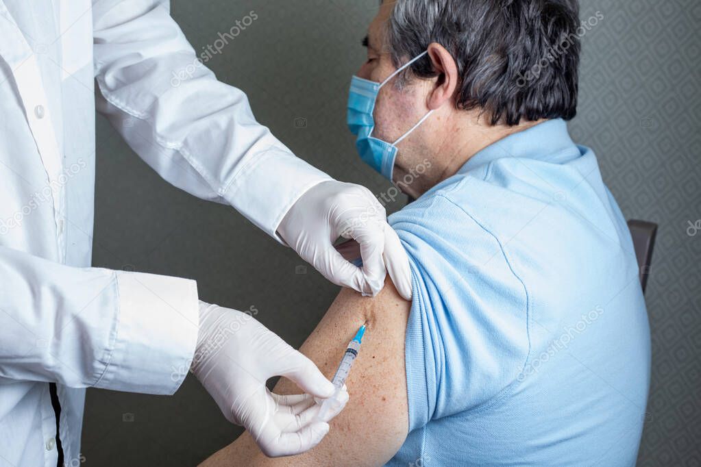 Antivirus vaccination for older people in clinic. General practitioner vaccinating an elderly patient against flu, influenza, pneumonia or coronavirus.