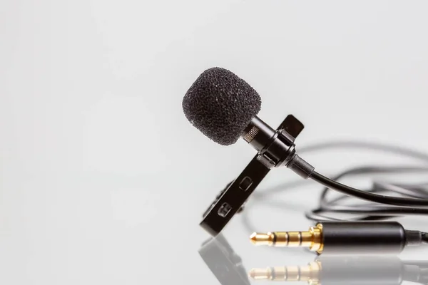 Beyaz arka planda klipsli küçük lavalier mikrofon ya da klapa mikrofonu. Cep telefonu için profesyonel ses kayıt ekipmanı.