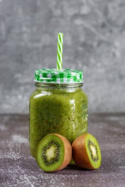 Sağlıklı taze meyve suyu gri beton arka planda kivi yarısıyla çevrili. Sağlıklı yaşam tarzı ve düzgün beslenme kavramı. Vitamin içeceği.