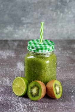 Sağlıklı taze meyve suyu, kivi limonu ve limonla çevrili gri beton arka planda. Sağlıklı yaşam tarzı ve düzgün beslenme kavramı. Vitamin içeceği.