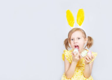 Tavşan kulaklı ve gri bir arka planda Paskalya için süslemeleri olan beyaz bir kızın portresi. Metin eklenecek yer ile paskalya arkaplanı.