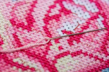 Çapraz dikişli tuvalin üzerinde bir iplikle dikiş iğnesine yakın çekim