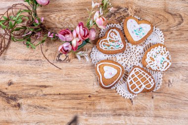 Ev yapımı kalp şeklinde kurabiyeler, üzerine beyaz krema serpilmiş.