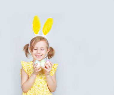 Tavşan kulaklı ve gri bir arka planda Paskalya için süslemeleri olan beyaz bir kızın portresi. Metin eklenecek yer ile paskalya arkaplanı.