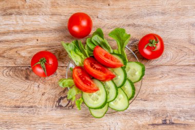 Ahşap arka planda bir tabakta salatalık ve domates dilimleme. Üst manzara..