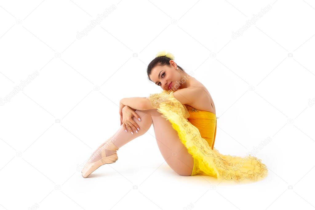 Young modern ballerina with yellow tutu doing the pose on white background.
