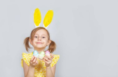 Tavşan kulaklı ve gri bir arka planda Paskalya için süslemeleri olan beyaz bir kızın portresi. Metin eklenecek yer ile paskalya arkaplanı.