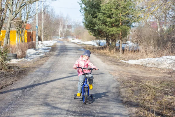Küçük Kız Köyde Kar Henüz Erimemişken Güvenlik Tekerlekleriyle Bisiklet Sürmeyi — Stok fotoğraf
