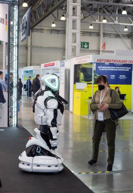 Moskova, Rusya - 14 Nisan 2021: Bir sergi ziyaretçisi Uluslararası Ulaştırma ve Lojistik Hizmetleri sergisindeki tribünlerden birinde akıllı bir robotla temasa geçti