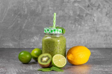 Gri beton arka planda taze kivili kivi ve ıspanaklı smoothie. Sağlıklı yaşam tarzı ve düzgün beslenme kavramı. Sağlığın için iyi. Vitamin içeceği.