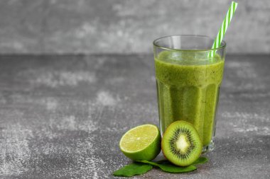 Gri beton arka planda meyvelerle çevrili uzun bir bardakta taze, sağlıklı meyve suyu. Uygun beslenme, kilo kaybı, vücudun zehirlenmesinden arınması..