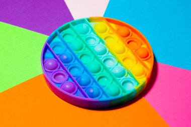 Duyusal oyuncağın üst görüntüsü çok renkli arka planda. Gökkuşağı rengi. Çocuklar ve yetişkinler için stres önleyici oyuncak..
