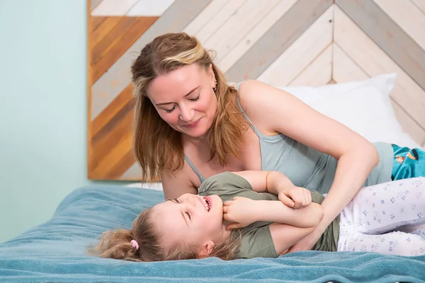 Portrait of mother with daughter lying on the bed in the bedroom — Stock Photo, Image