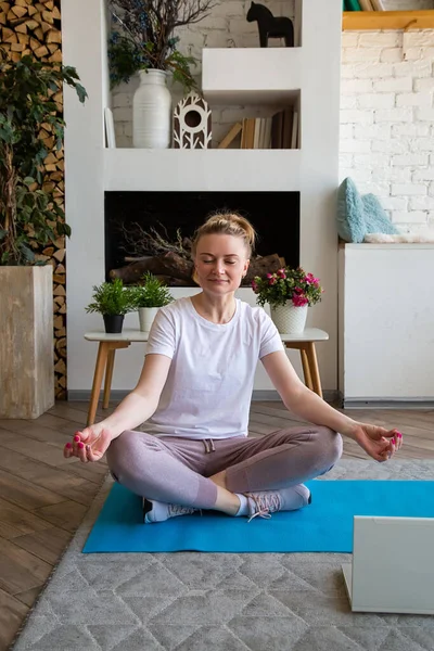 Portrait of young woman doing yoga online sitting in lotus position on yoga mat — Stock Photo, Image