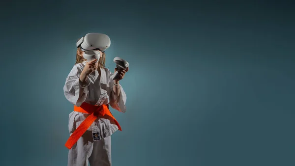 スタジオ仮想現実ヘッドセットでビデオゲームをプレイする空手の制服を着た若い白人女の子の肖像や オンラインで練習 着物Kyokushinkai上の刺繍テキスト バナー — ストック写真