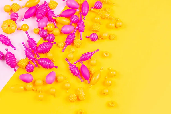 Close-up view of Multicolored plastic beads for a girl\'s bracelet from a set for needlework on a yellow background