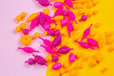 Renkli arkaplanda dikiş işi yapan bir kızın bilekliği için çok renkli plastik boncukların yakın plan görüntüsü.