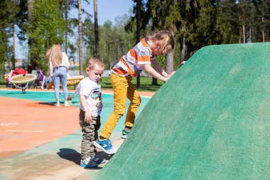 Küçük kız çocuk parkının duvarına tırmanıyor.