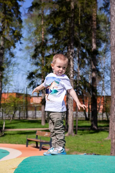 Liten pojke promenader genom territoriet av lekplatsen utomhus på solig dag. — Stockfoto