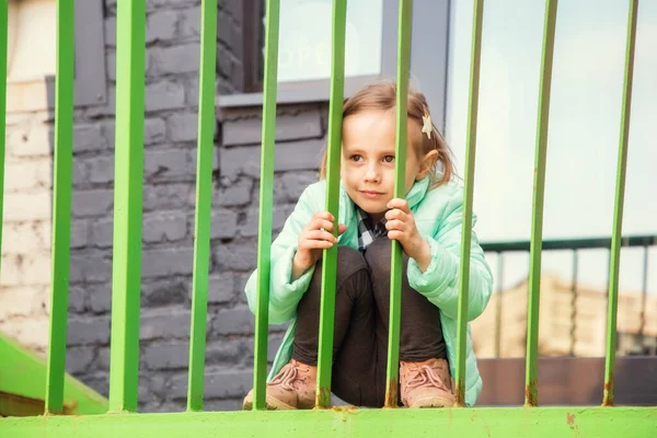 Adorable niña sentada con una cara aburrida en la escalera de hierro — Foto de Stock