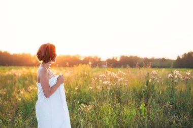 30-35 yaşlarındaki beyaz kadın yaz manzarasında gün batımında bir tarlada.