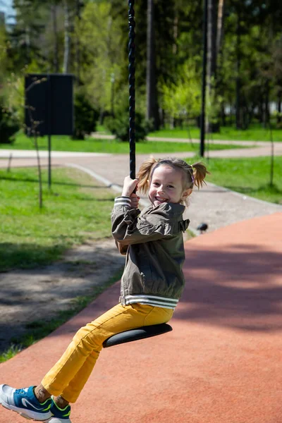 Niña Caucásica Monta Columpio Patio Recreo Sonríe Aire Libre Día — Foto de Stock