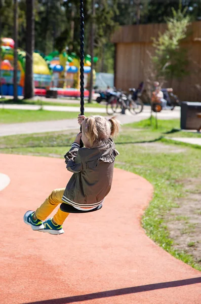 Caucasiano menina monta um bungee swing no playground — Fotografia de Stock