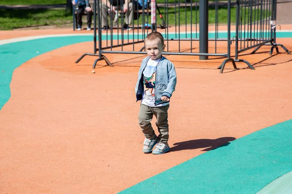 Menino caminha através do território do playground ao ar livre no dia ensolarado. — Fotografia de Stock