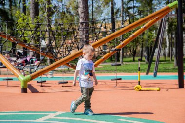 Kafkasyalı küçük çocuk güneşli bir günde oyun sahasının dışında yürüyor..
