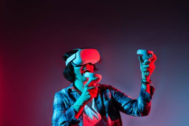 Beyaz kadın 35-40 yaş arası sanal gerçeklik kaskı takıyor. VR gözlükler, neon ışıkta teknoloji kavramı.