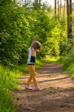 6 yaşında beyaz bir kız ormanda bir patikaya atlıyor.