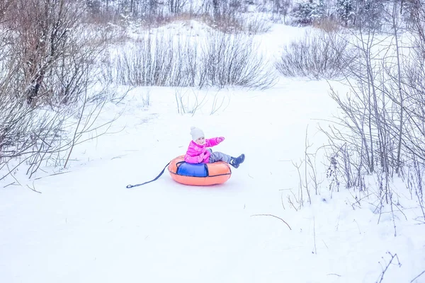 小女孩骑着充气滑雪板滑行下山 人与冬季运动 — 图库照片